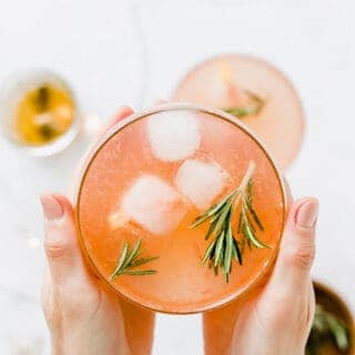 zwei hände halten einen grapefruit cocktail