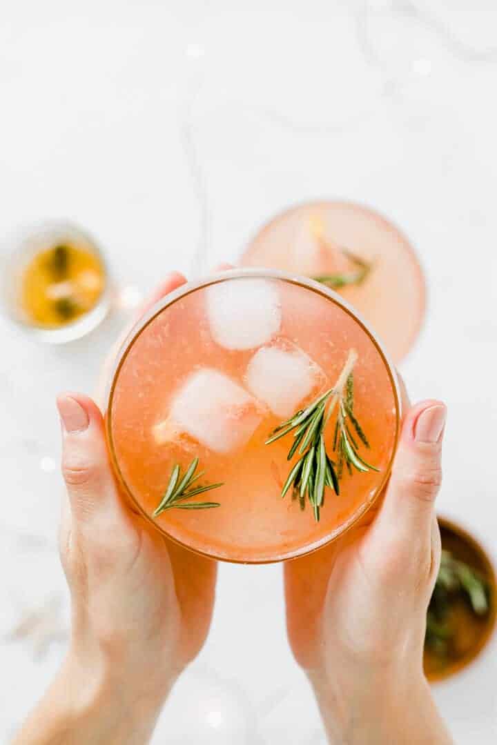 zwei hände halten einen grapefruit cocktail
