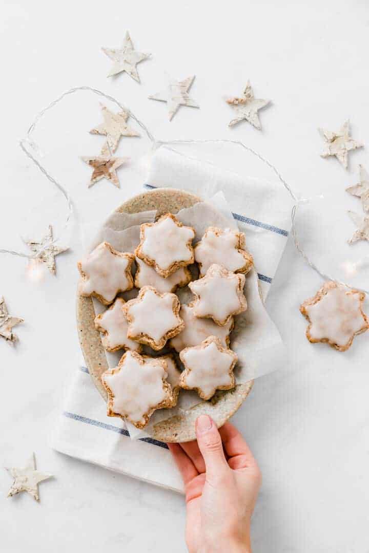 a hand holds a bowl with freshly bakes vegan star cookies