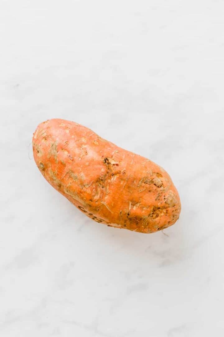 a large orange sweet potato on a white surface