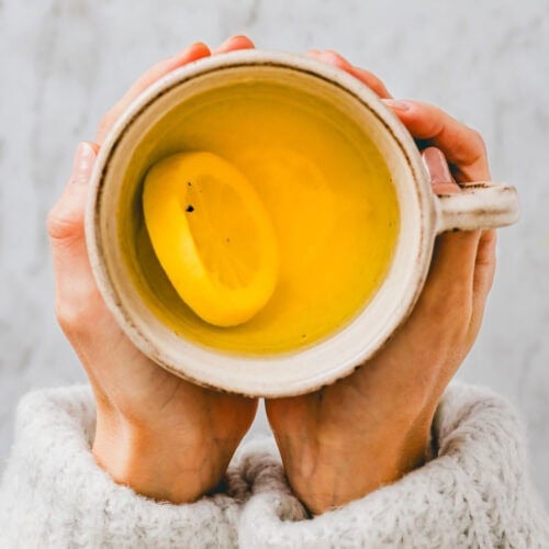two hand holding a cup of lemon ginger turmeric tea