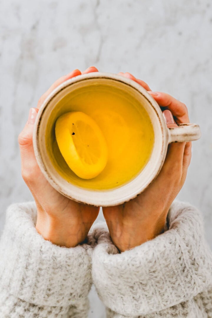 two hand holding a cup of lemon ginger turmeric tea