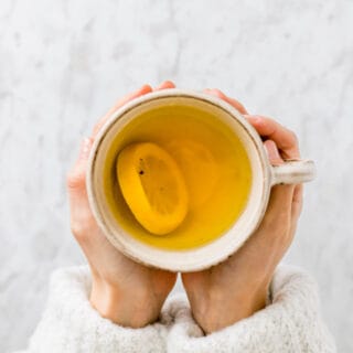 two hand holding a cup of ginger turmeric tea