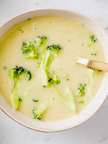 vegan broccoli potato soup served in a bowl with a golden spoon