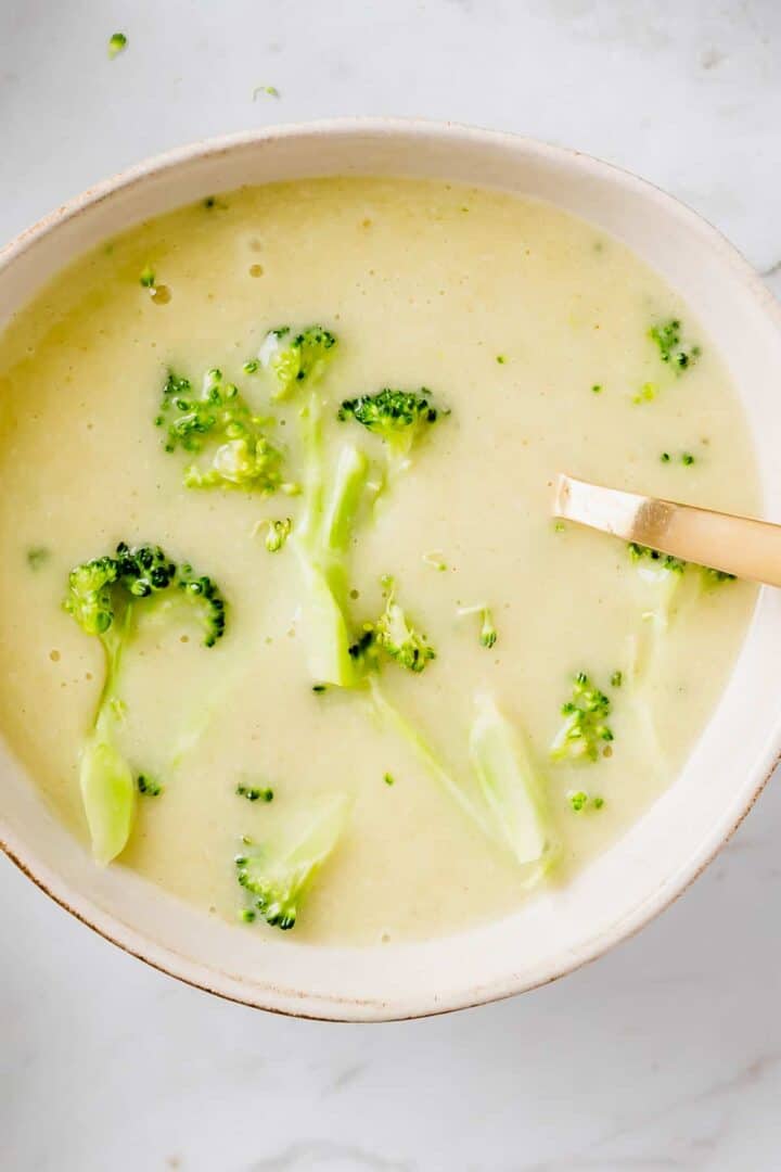 vegan broccoli potato soup served in a bowl with a golden spoon