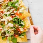 a hand grabbing vegan nachos