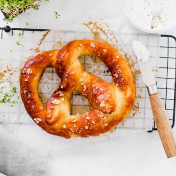 eine vegane brezel serviert mit veganem frischkäse und kresse