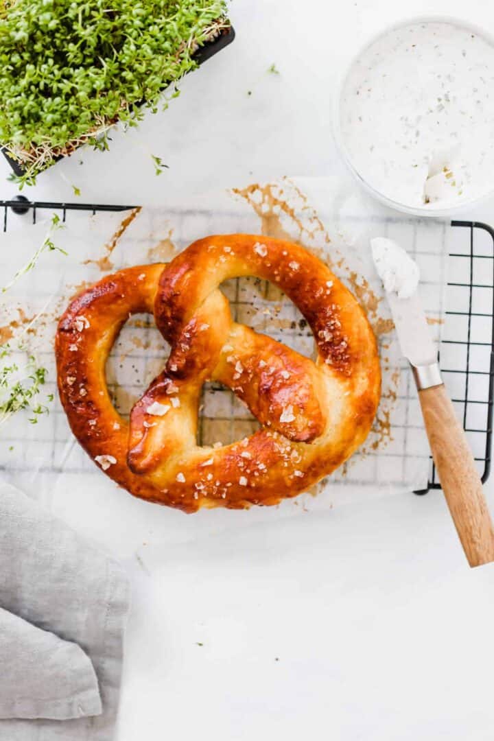 vegan pretzel on a black tray next to garden cress