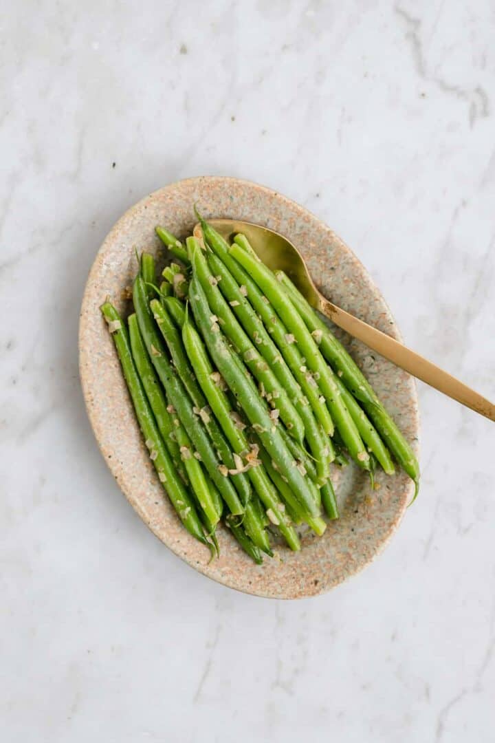 cooked green beans with garlic and shallots served on a plate