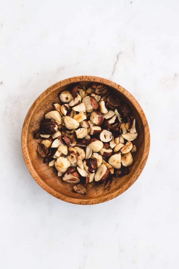 toasted and chopped hazelnuts in a wooden bowl