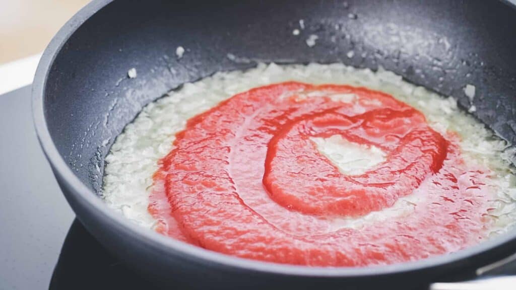 tomato puree with garlic and onion in a skillet