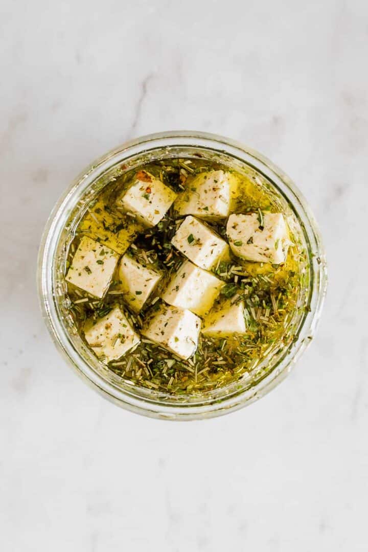 vegan tofu feta with olive oil and herbs in a mason jar