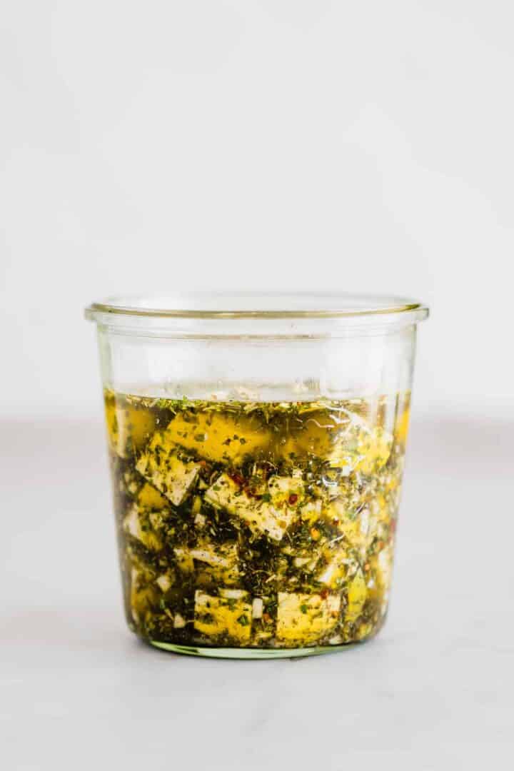 vegan tofu feta with olive oil and herbs in a mason jar