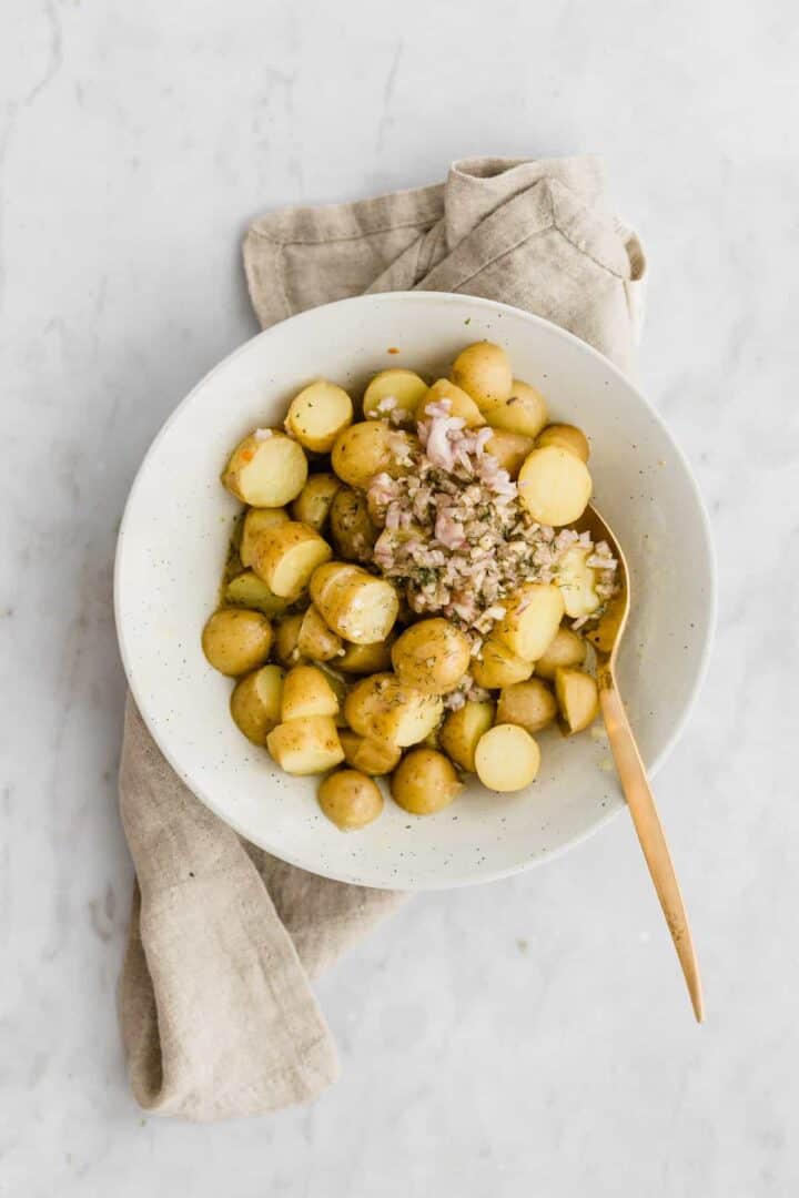 veganer kartoffelsalat in blauen teller mit einem goldenen löffel