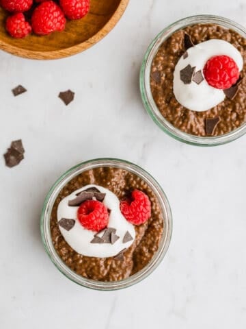 schoko chia pudding mit veganer schlagsahne, himbeeren, und schoko flakes