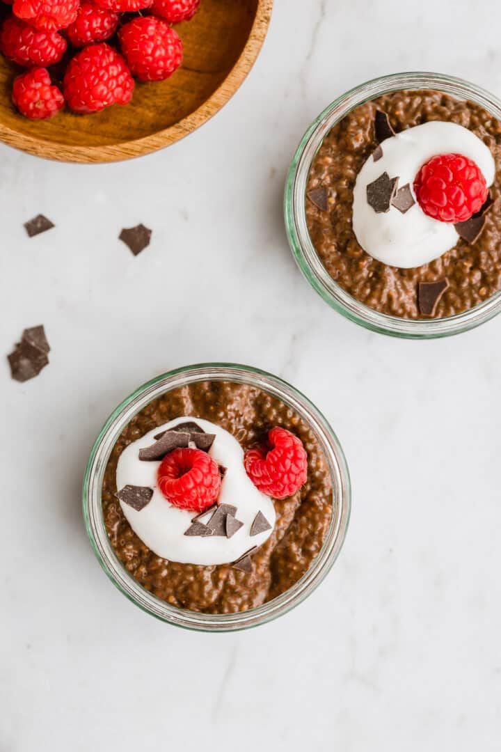 schoko chia pudding mit veganer schlagsahne, himbeeren, und schoko flakes