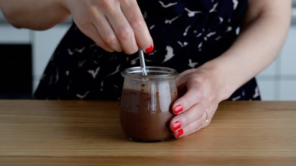 one hand stirring chocolate chia pudding using a whisk