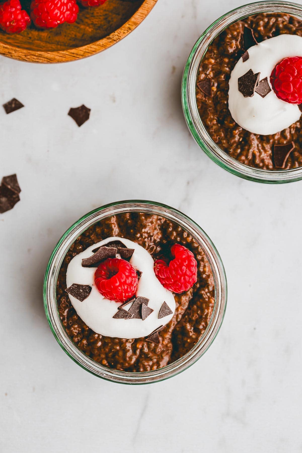 schoko chia pudding in zwei gläsern mit himbeeren dekoriert