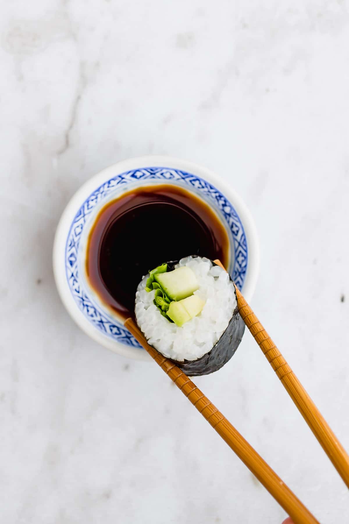 two chopsticks dipping a sushi into soy sauce