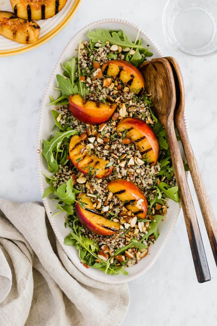 a plate with grilled peach salad, quinoa, and arugula