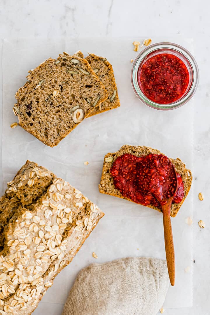 a loaf of bread next to a slice of bread spread with raspberry jam