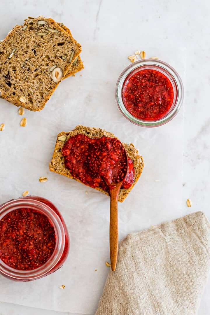 a loaf of bread next to a slice of bread spread with homemade jam