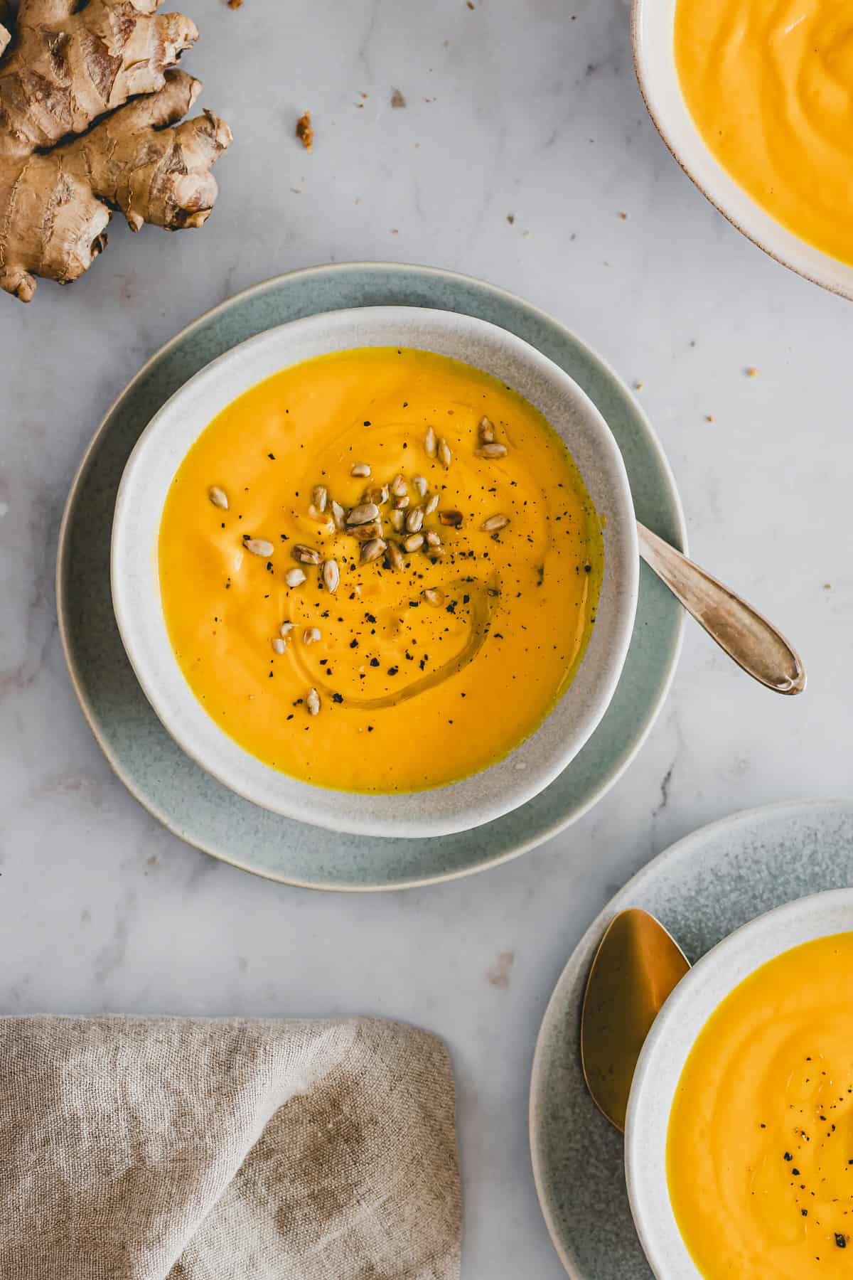 carrot ginger soup in a bowl topped with sunflower seeds