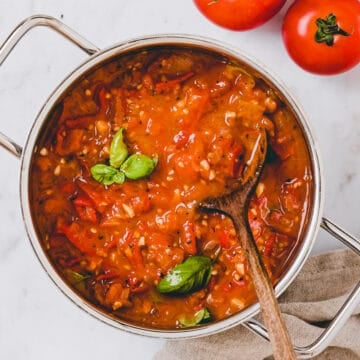 frisch eingekochte tomatensauce in einem topf neben tomaten
