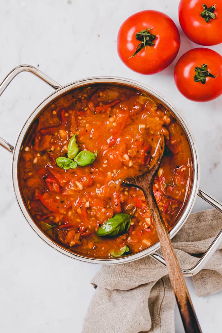 frisch eingekochte tomatensauce in einem topf neben tomaten