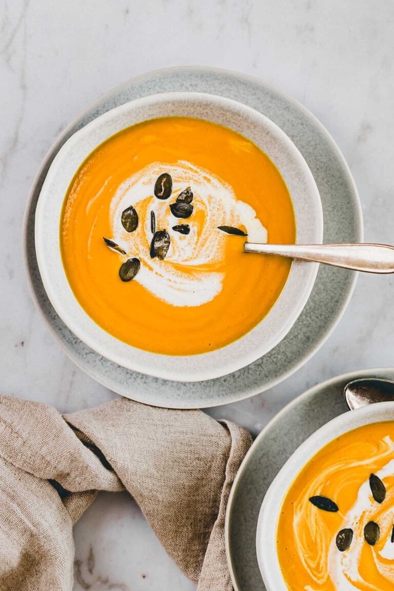 Kürbis Karotten Ingwer Suppe in zwei schälchen mit einem löffel