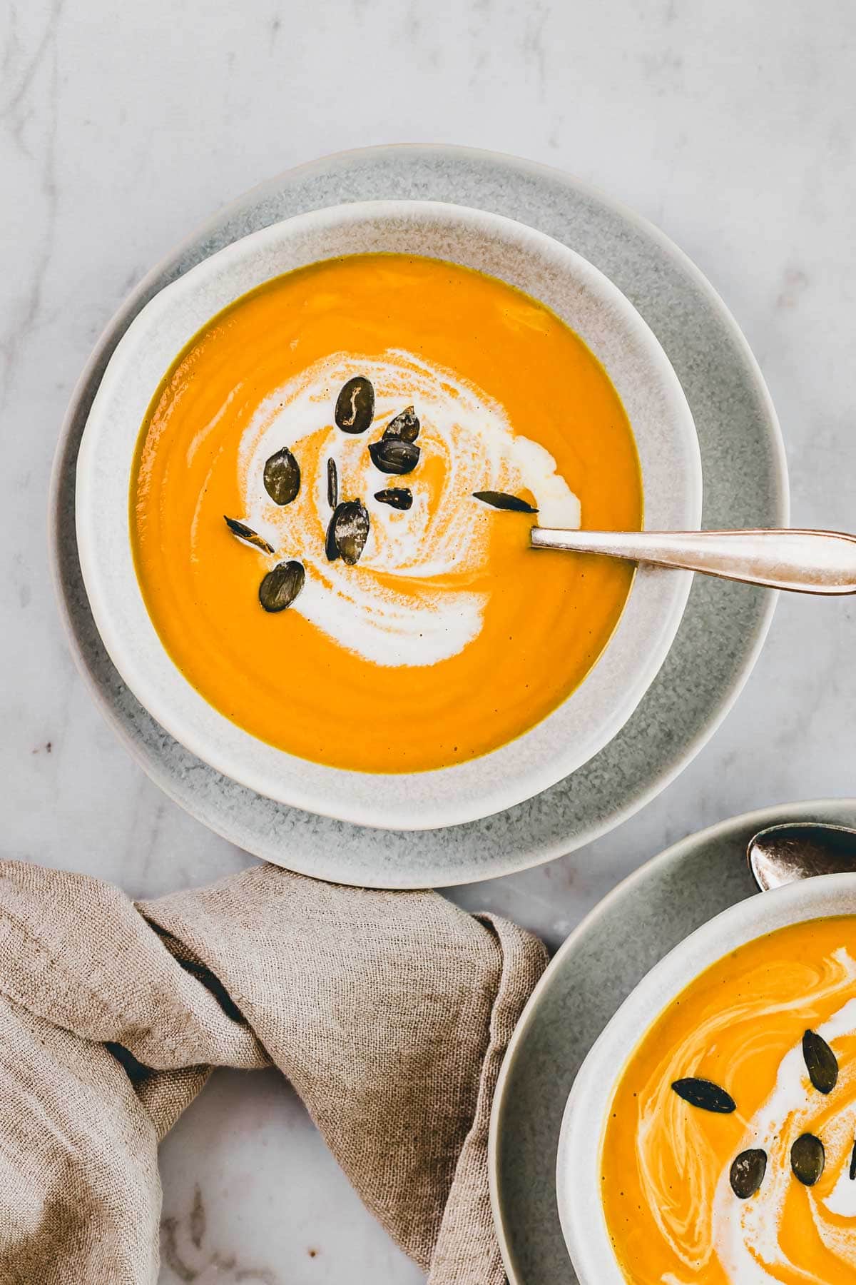 Pumpkin Ginger Soup with coconut milk served in two small bowls