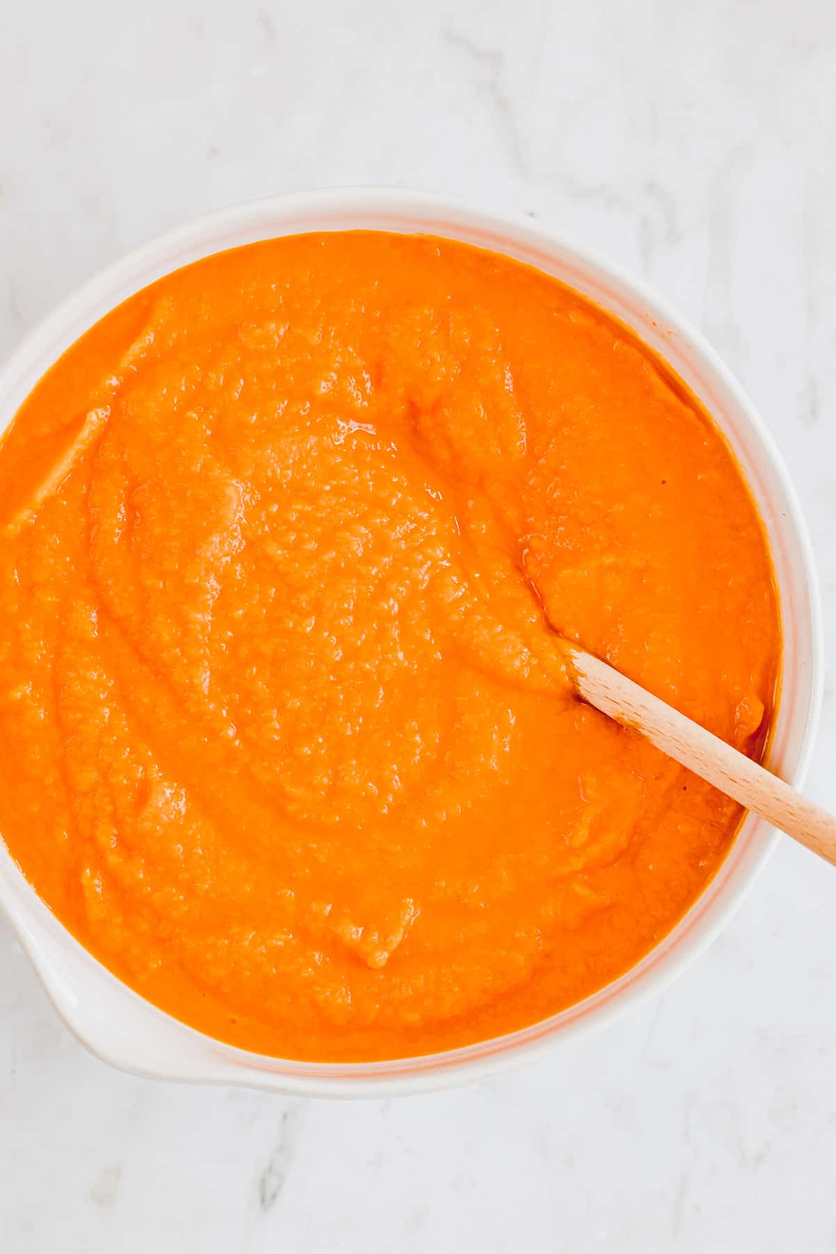 homemade pumpkin puree in a bowl with a wooden spoon