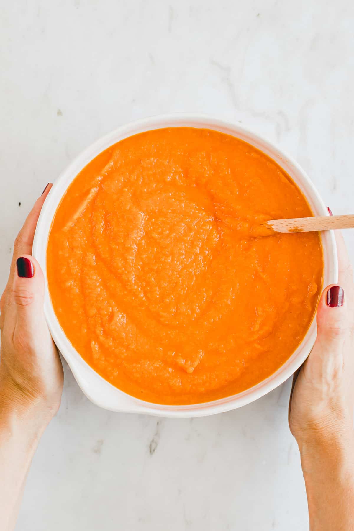 two hands holding a bowl of pumpkin puree