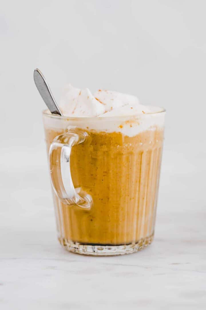 pumpkin spice latte with dairy-free whipped cream in a glass mug