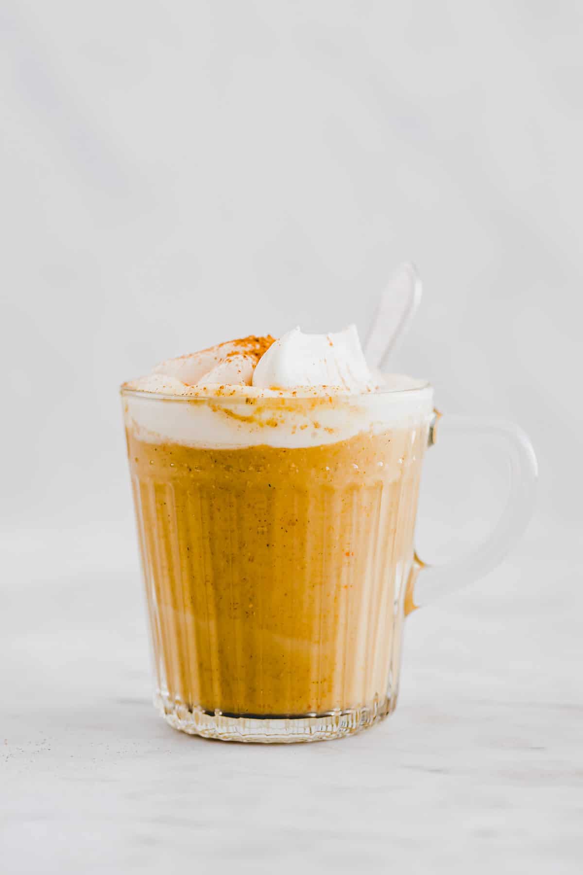 pumpkin spice latte in einer glastasse mit einem löffel