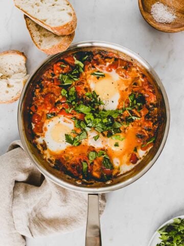 shakshuka in einer pfanne mit frischem kräutern dekoriert