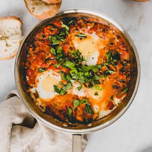 shakshuka in a skillet topped with fresh herbs