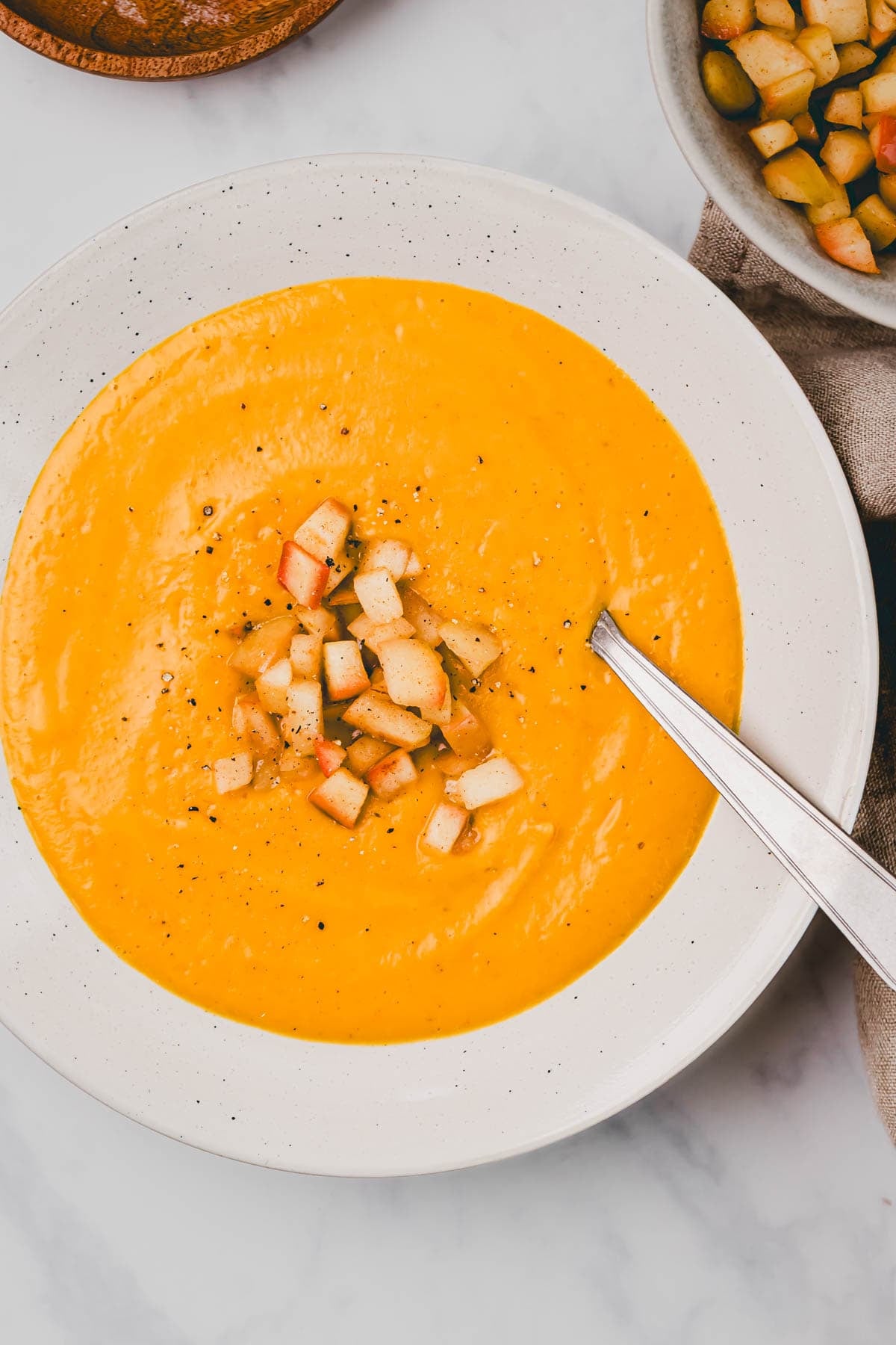 Süsskartoffelsuppe mit Kokosmilch und Apfel Topping in einem teller