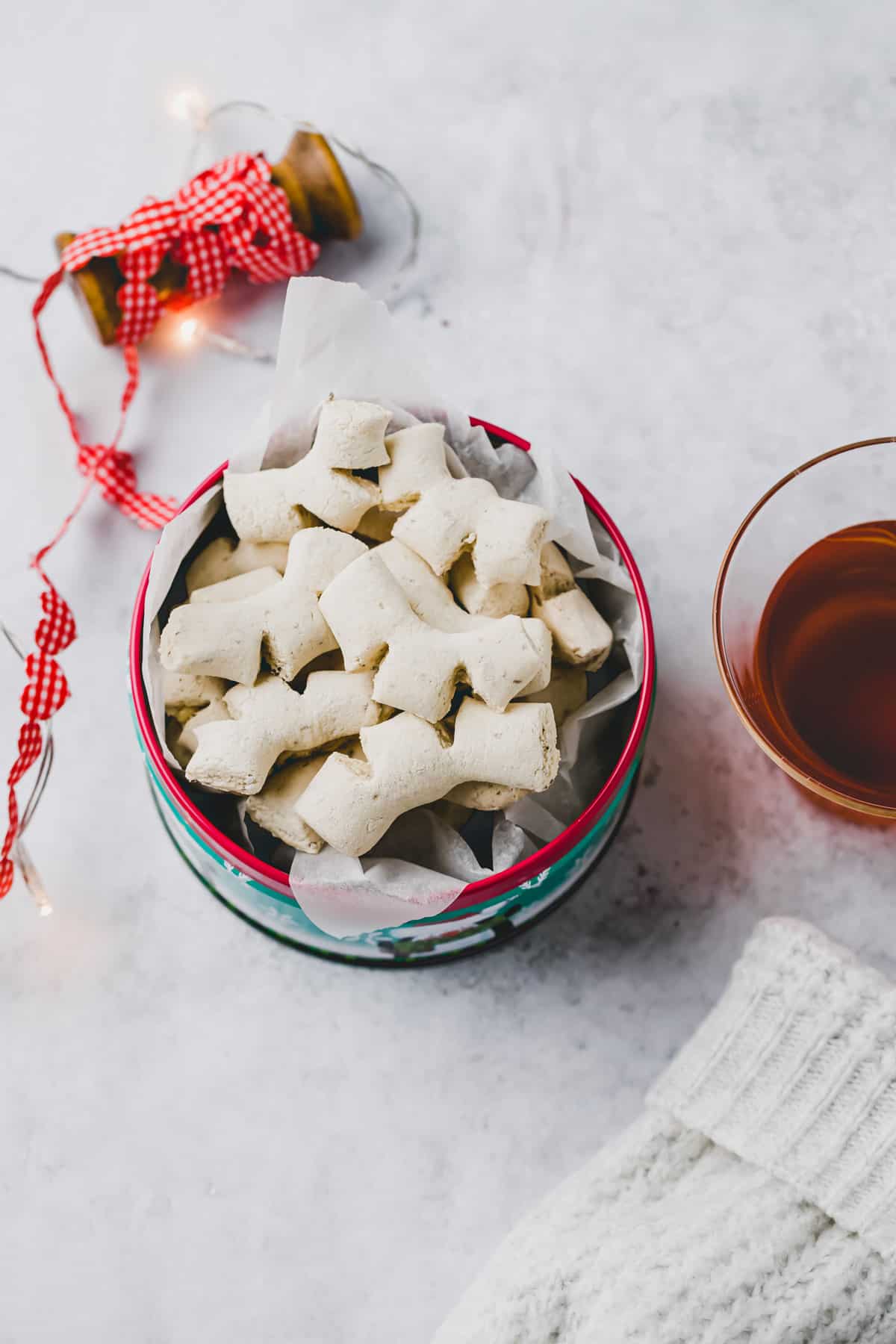 anise cookies in a cookie tin next to a cup of tea