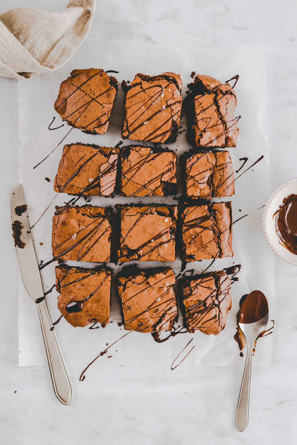 crinkle top brownies on a parchment paper topped with melted chocolate