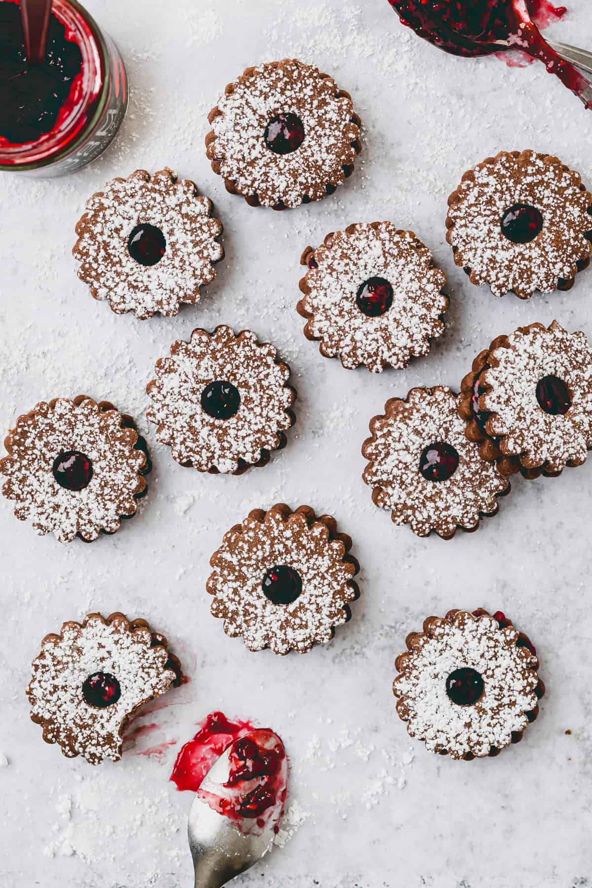 raspberry linzer cookies next to a jar raspberry jam