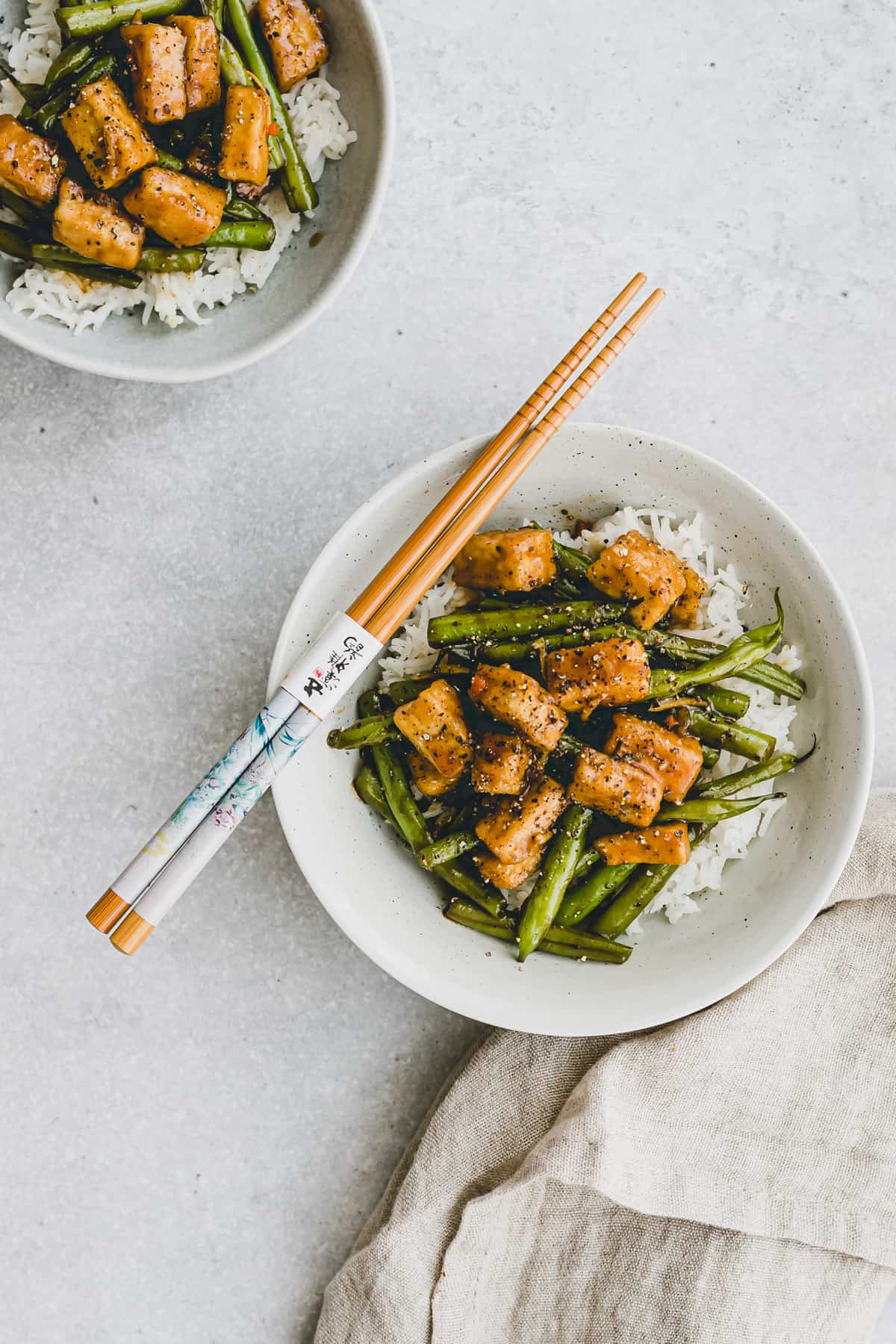 zwei schüssel gebratener tofu und grünen bohnen auf reis