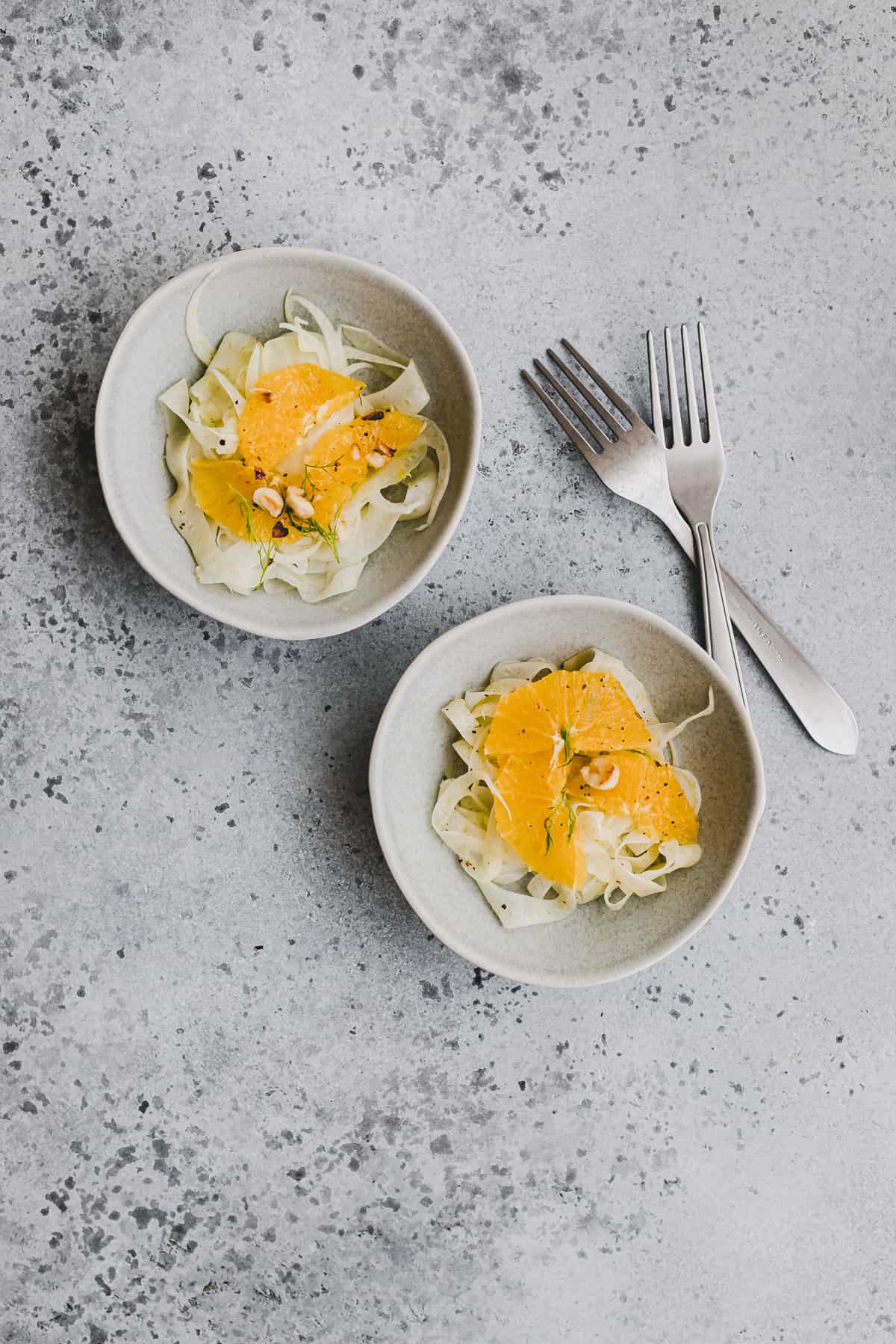 orangen fenchel salat in kleinen schalen neben zwei gabeln