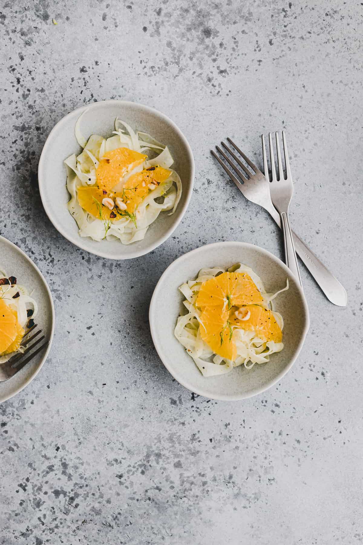 fennel salad with orange and toasted hazelnuts in bowls next to forks