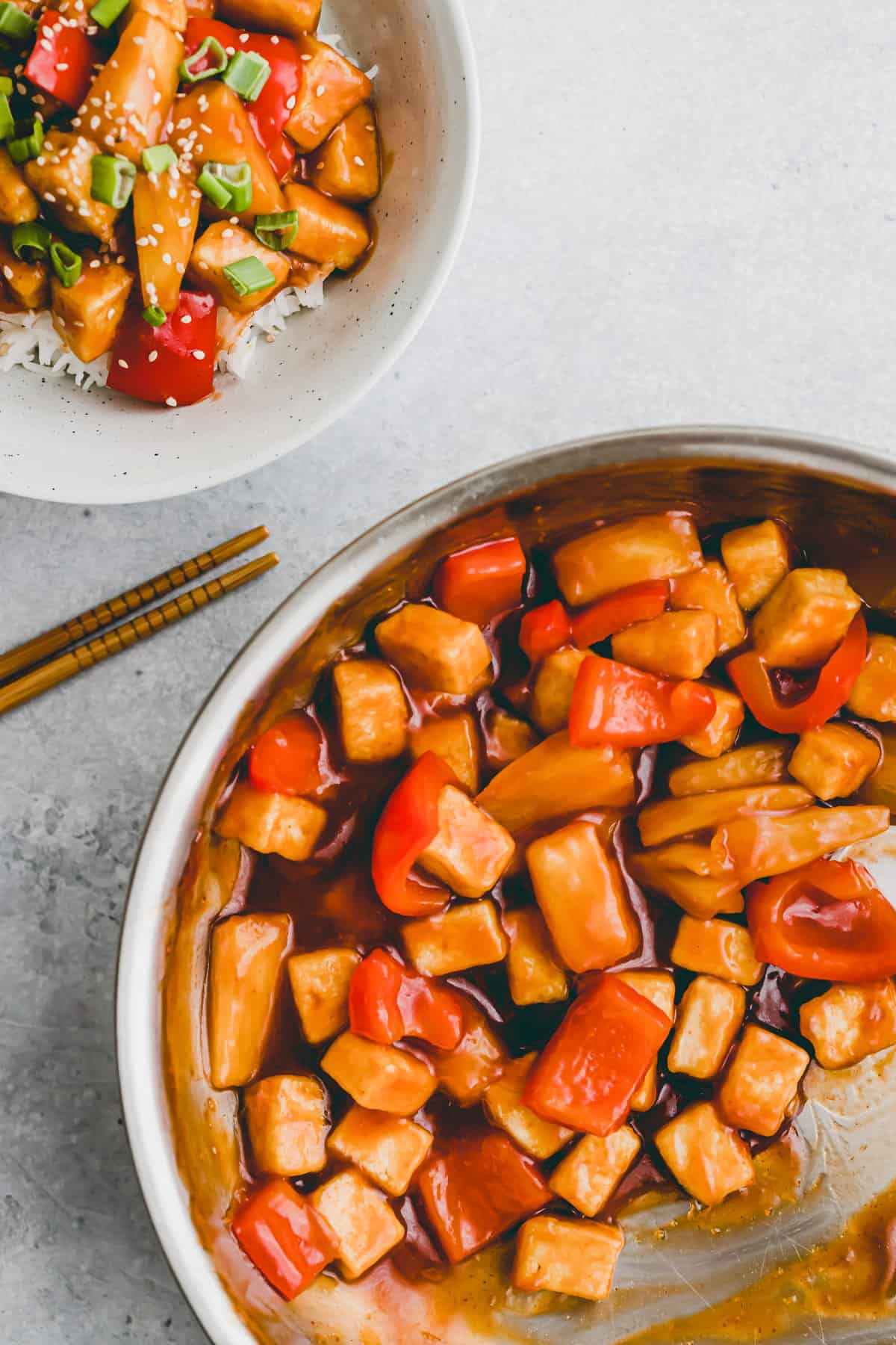 eine pfanne mit süß sauer soße, tofu, und paprika