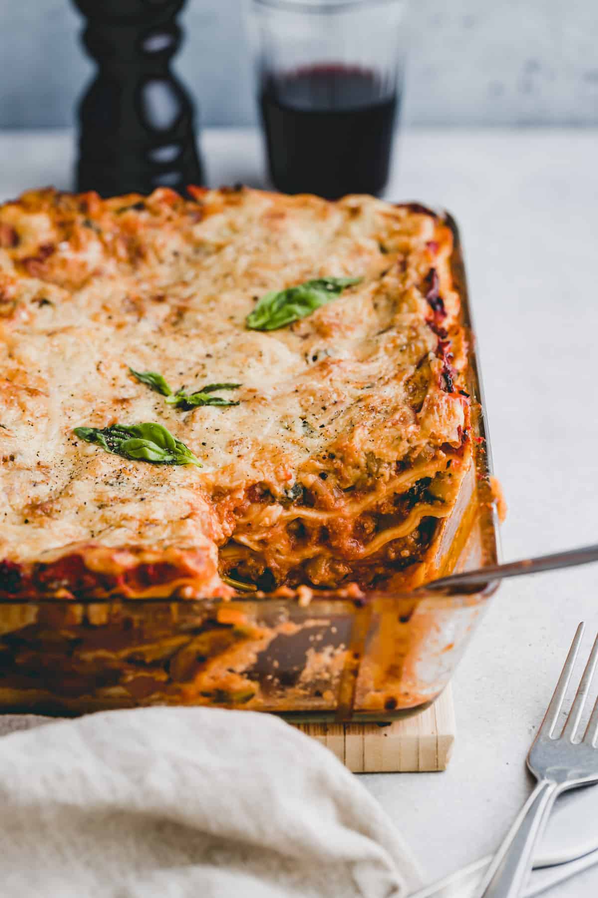 angeschnittene vegetarische lasagne neben einem glas rotwein