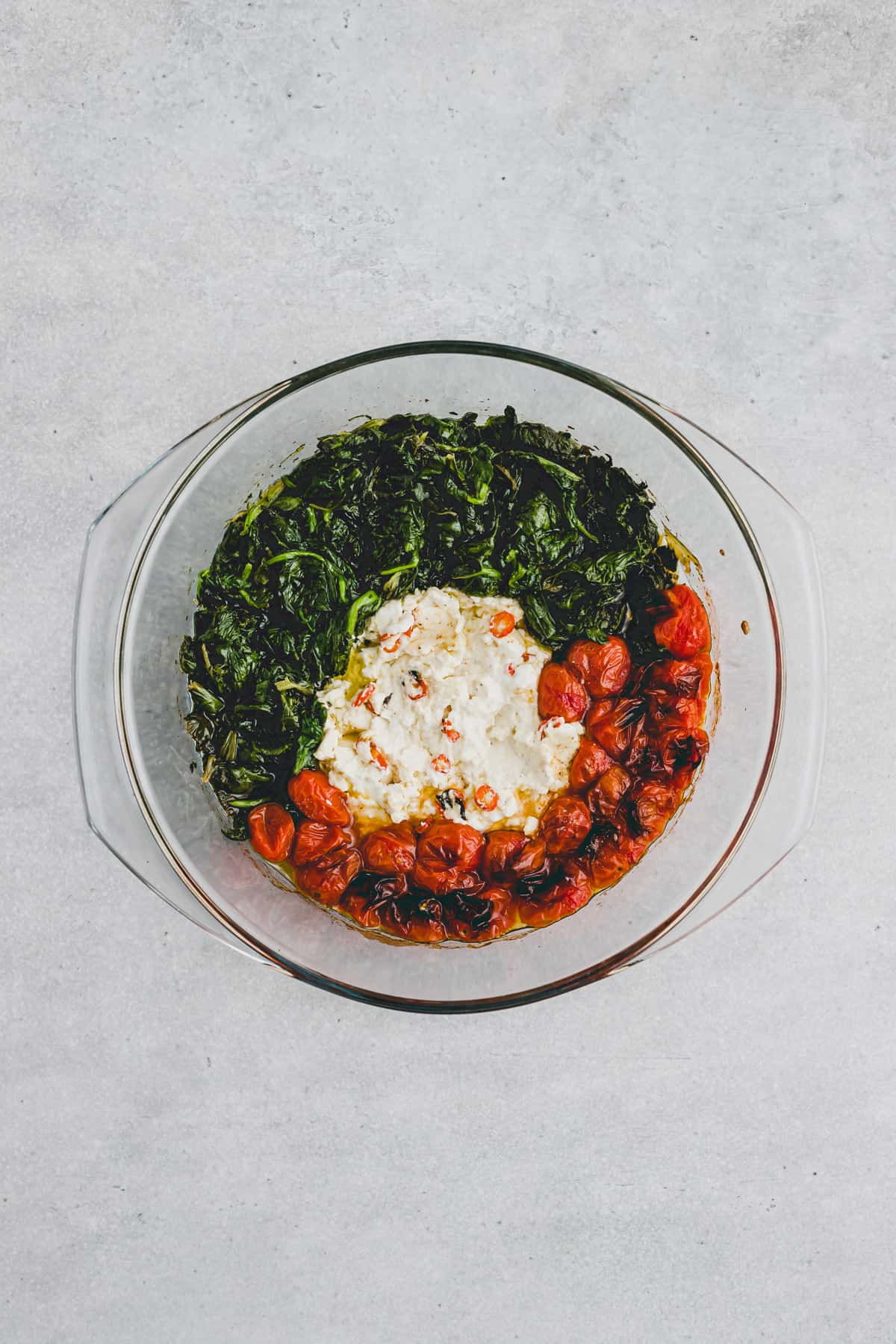 creamy baked feta with spinach and cherry tomatoes in a baking dish