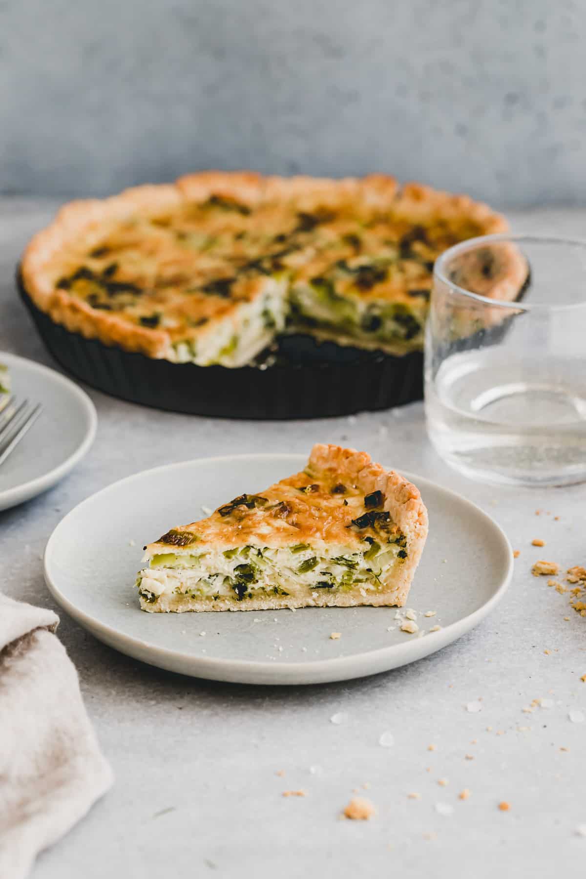 a slice of leek and cheese quiche on a blue plate