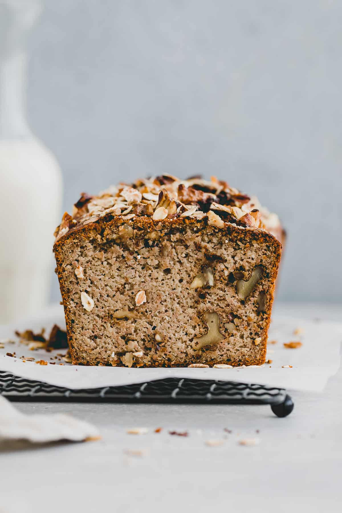 a loaf gluten-free walnut banana bread next to a bottle of dairy-free milk