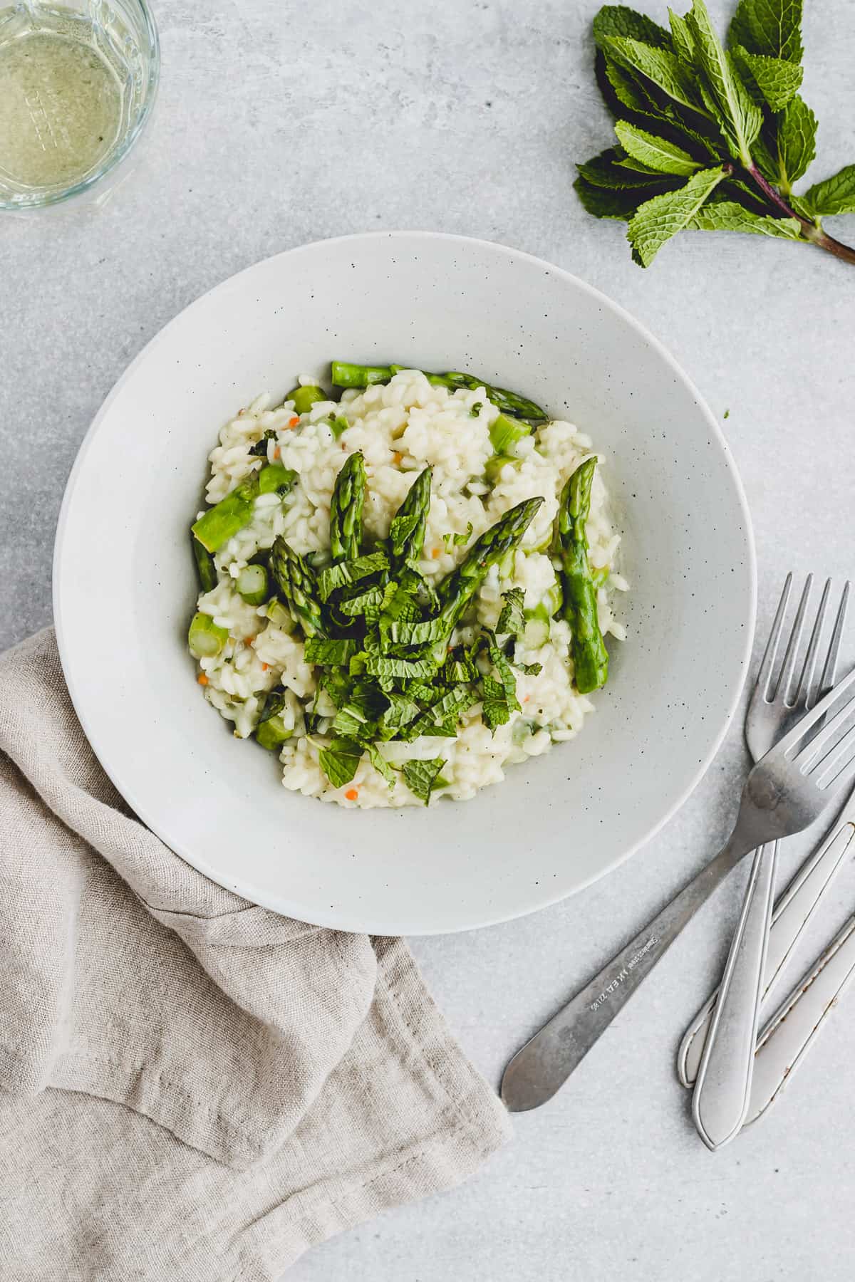 ein teller mit veganem spargelrisotto und frischer minze